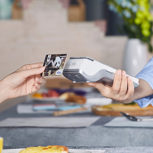 Person holding card up to card machine to pay using the contactless payment method