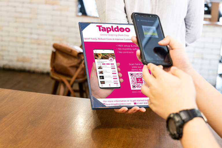 Person scanning QR code on Tapldoo leaflet with their phone